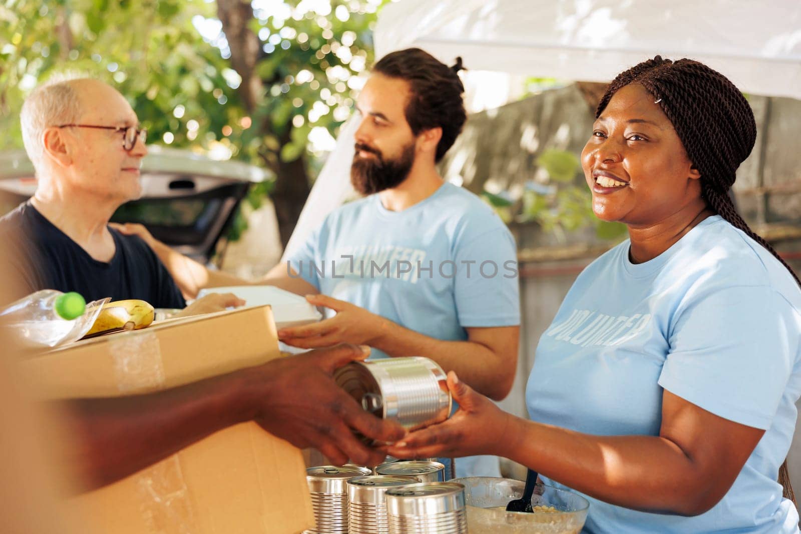 African american and caucasian volunteers provide aid, giving donation boxes filled with non-perishable items to the poor. Multiethnic team helps fight hunger and poverty through charitable efforts.