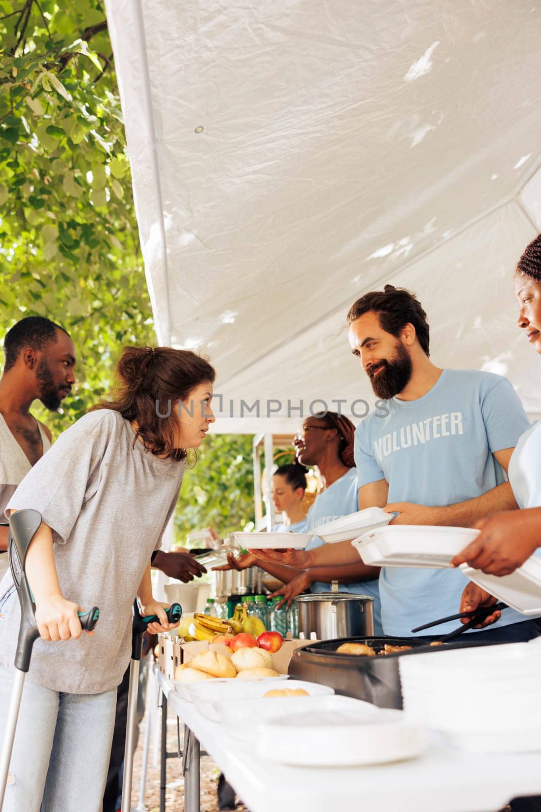 Multiethnic charity group gives back, providing free food, shelter, and support to the less fortunate. Smiling and happy volunteers helping the homeless, sick, and disadvantaged individuals in need.