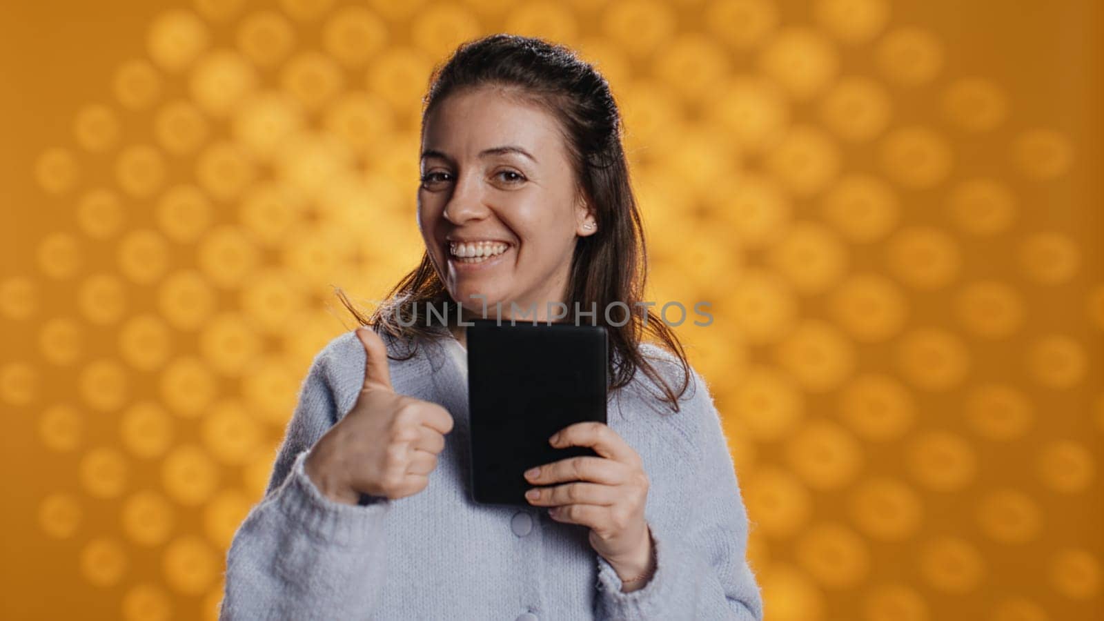Woman choosing between physical books and ebooks, favoring ereader for lightness, studio background. Bookworm picking digital literature on tablet in front of heavy stack of novels, camera B