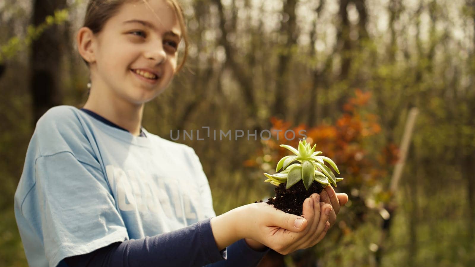 Cute child activist presenting a small seedling tree in her hands by DCStudio