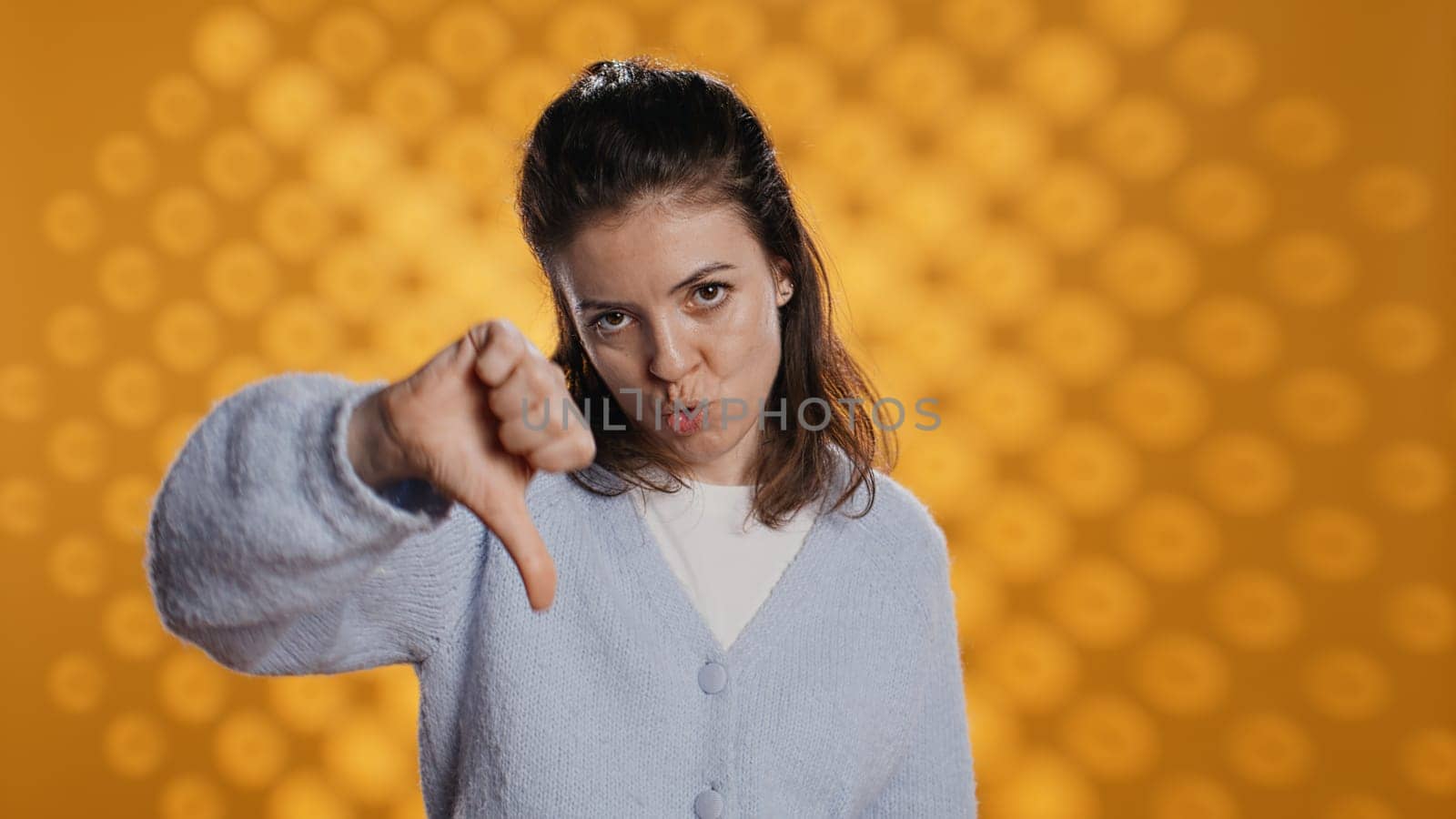 Disappointed woman bashing book, showing thumbs down sign, studio background by DCStudio