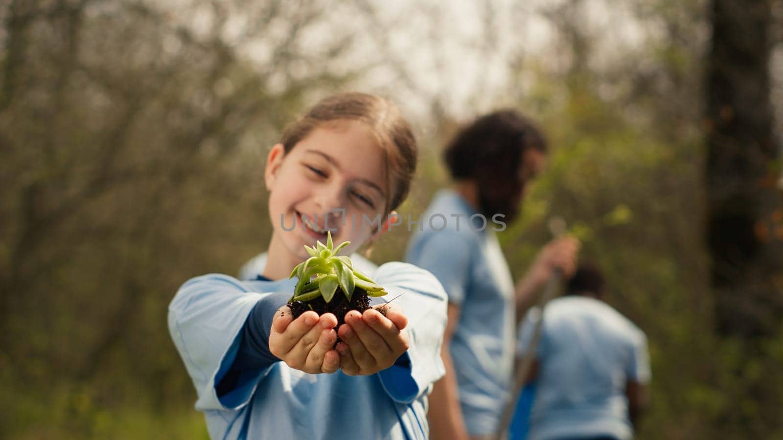 Little kid volunteer holding a small seedling with natural soil in hands by DCStudio