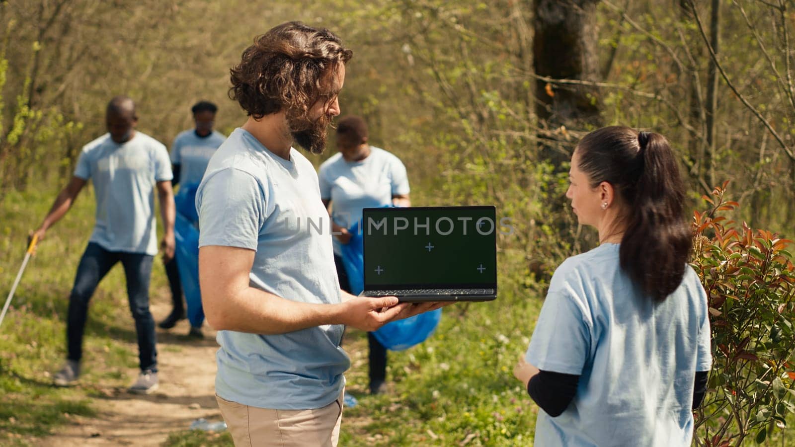 Team of climate and nature activists using laptop with greenscreen near a forest by DCStudio