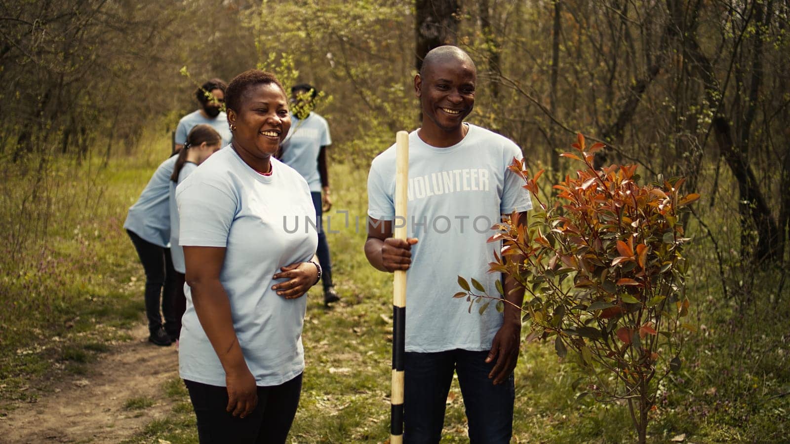 Portrait of couple volunteering to plant trees and collect trash from the woods by DCStudio