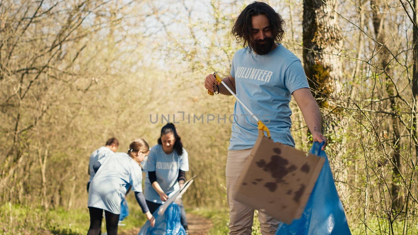 Man activist using tongs to grab garbage and plastic waste by DCStudio