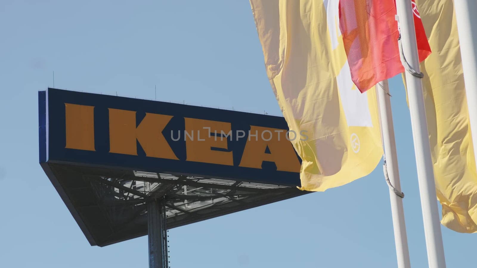 IKEA flags waving in the wind against sky and signboard. by vladimka