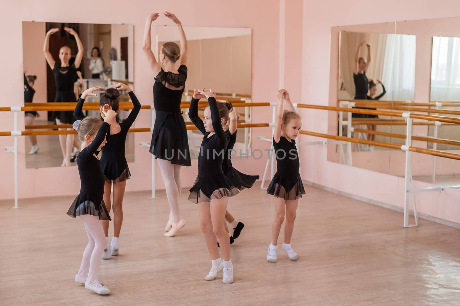 Children's ballet school. Caucasian woman teaching ballet to little girls