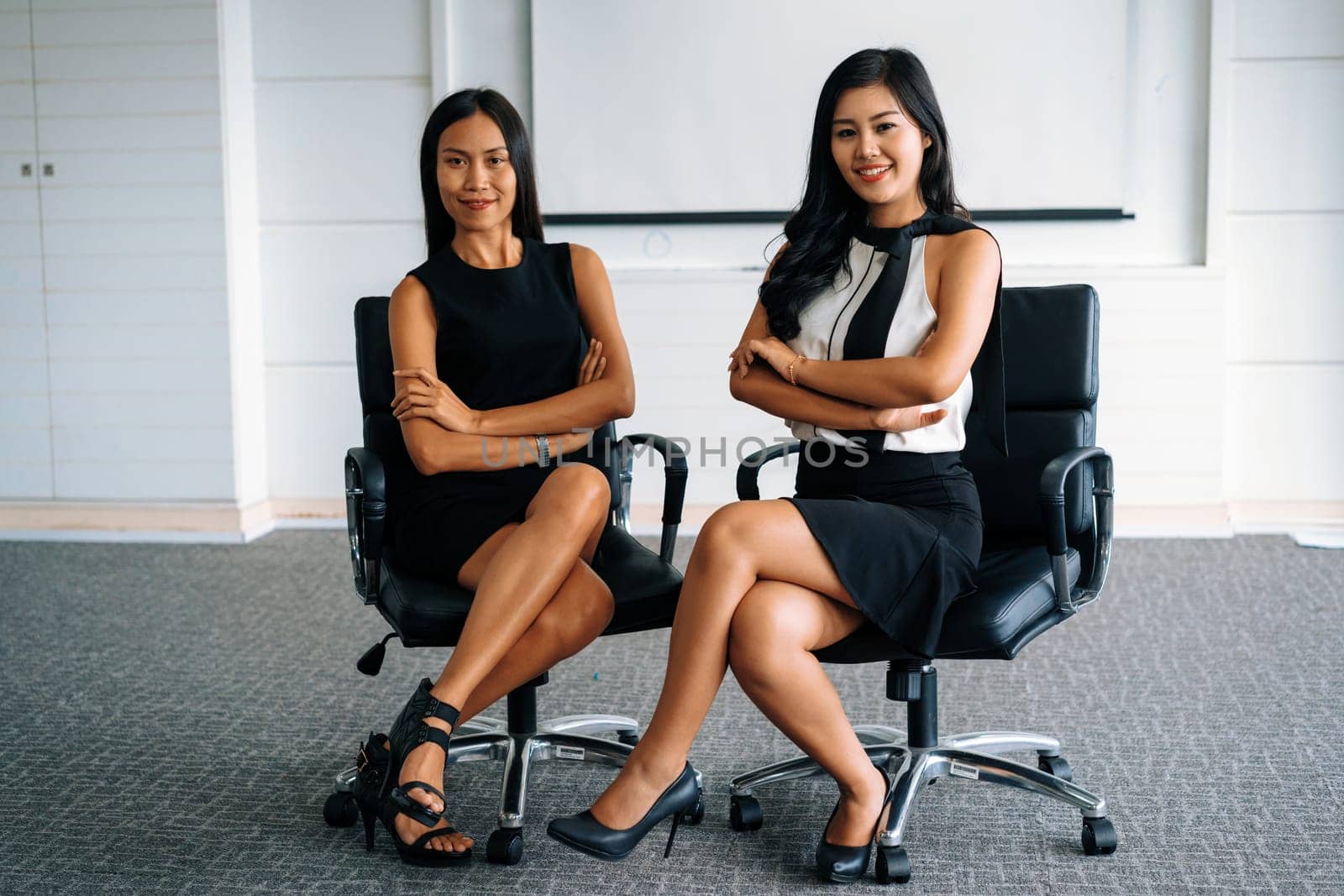 Two young Asian businesswomen sitting in office. Business friends and community concept. uds