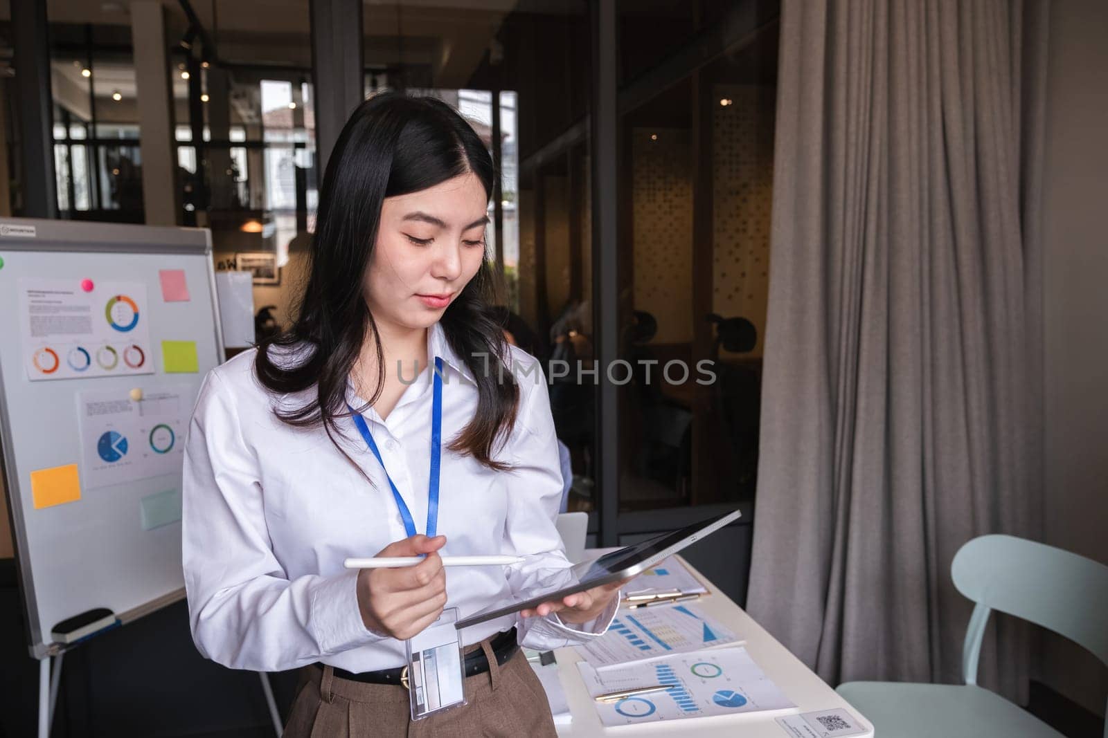 Portrait of a confident young businesswoman standing with a tablet at a conference room in her office..