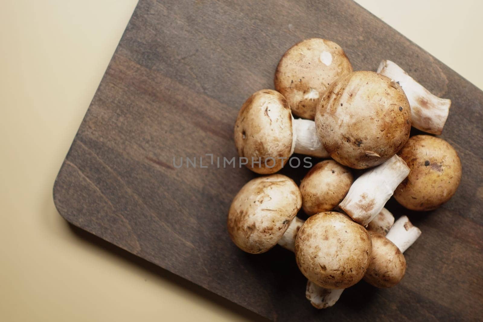 Fresh whole and halved brown mushrooms on a wooden cutting board ,