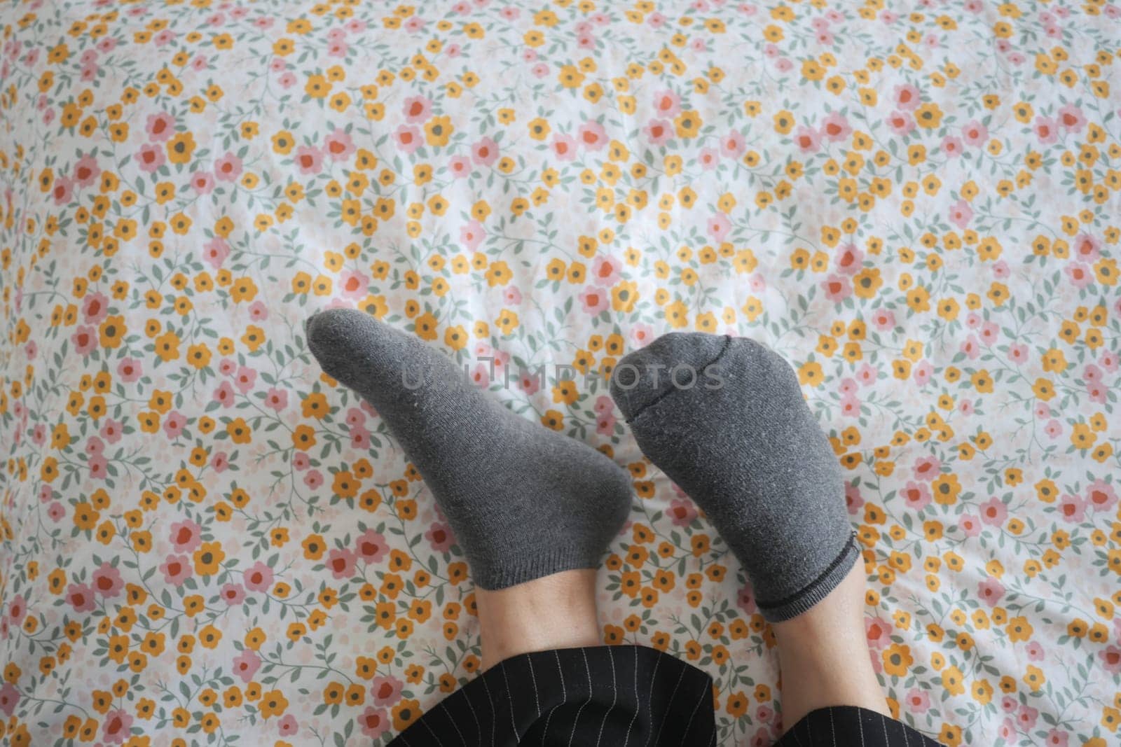 a woman is laying on a bed with their feet up and wearing socks.
