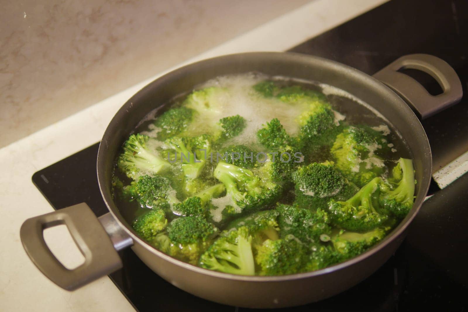 cooking broccoli in pan on electric stove by towfiq007