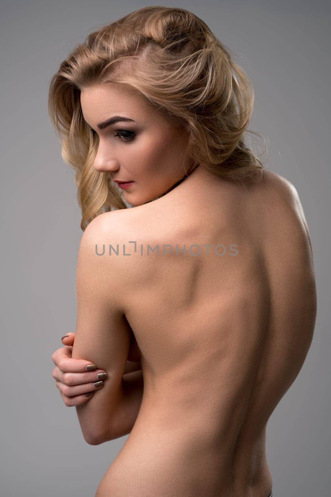 Portrait of beautiful nude blonde posing back to camera
