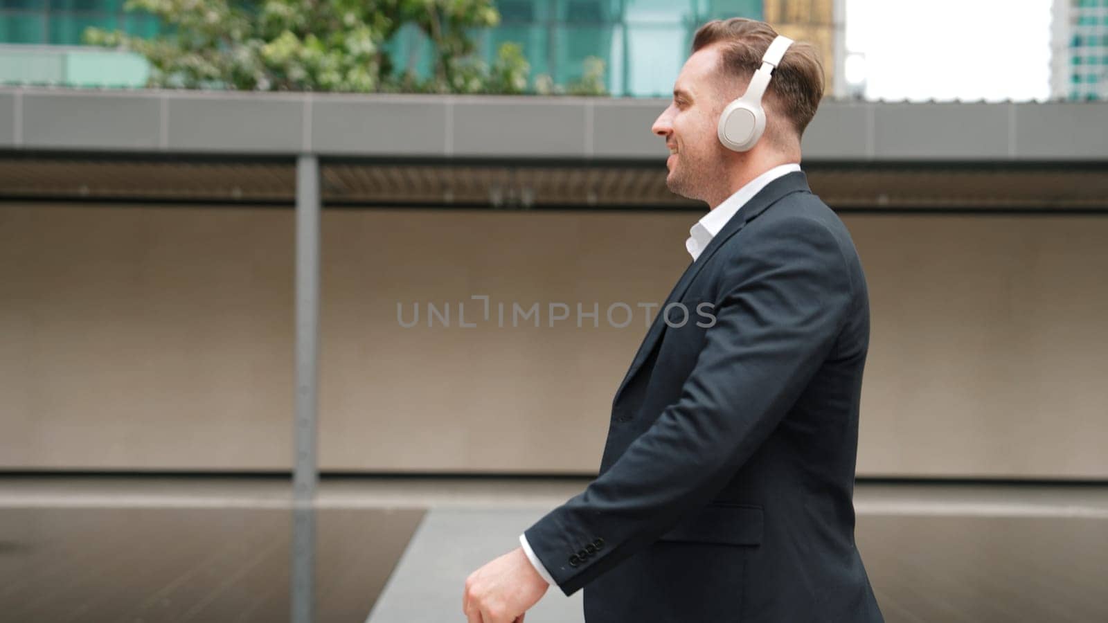 Project manager with headphone walking workplace while moving to music. Urbane. by biancoblue