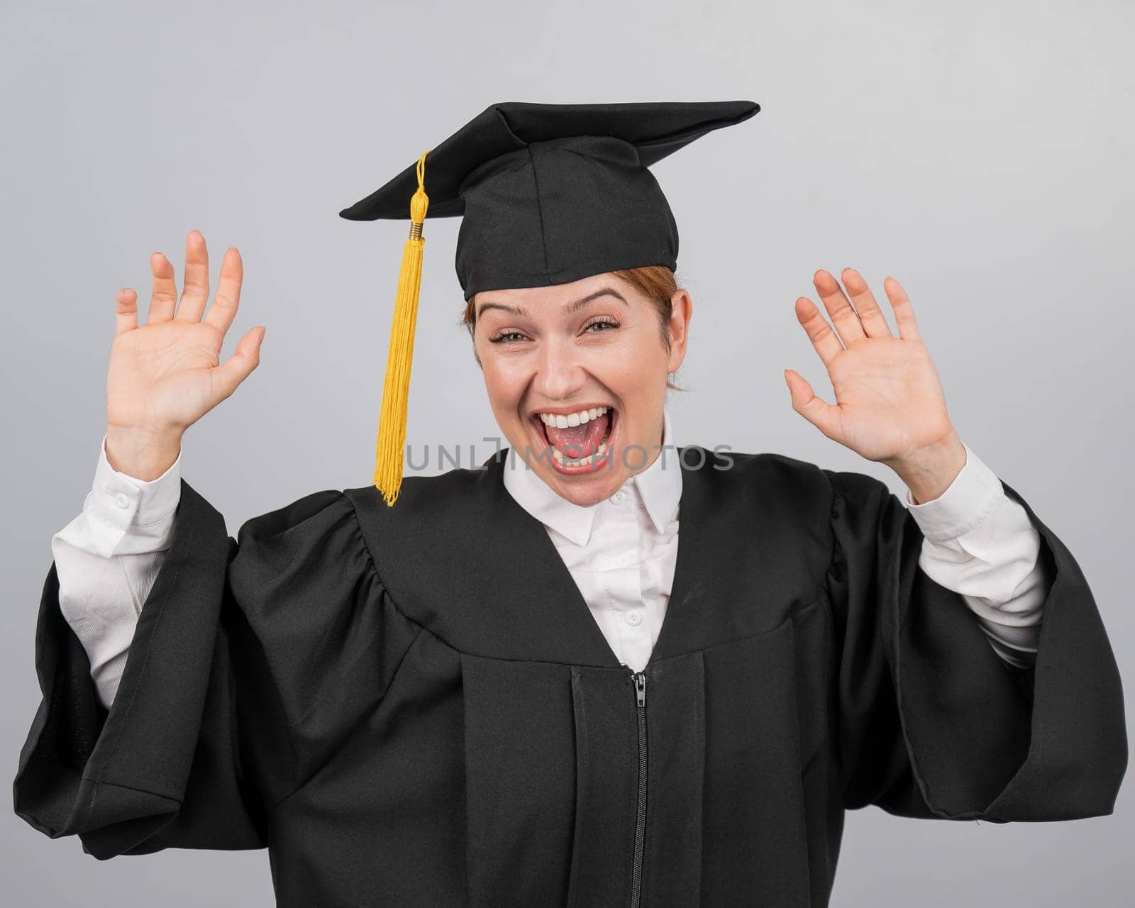 Caucasian woman dancing in graduation gown on white background. by mrwed54