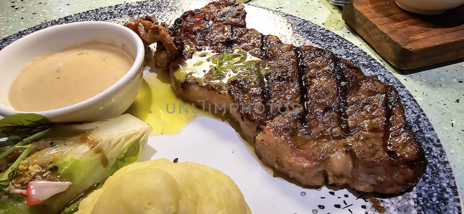Sirloin steak grilled medium rare served with potatoes and salad with mushroom black pepper sauce in a restaurant