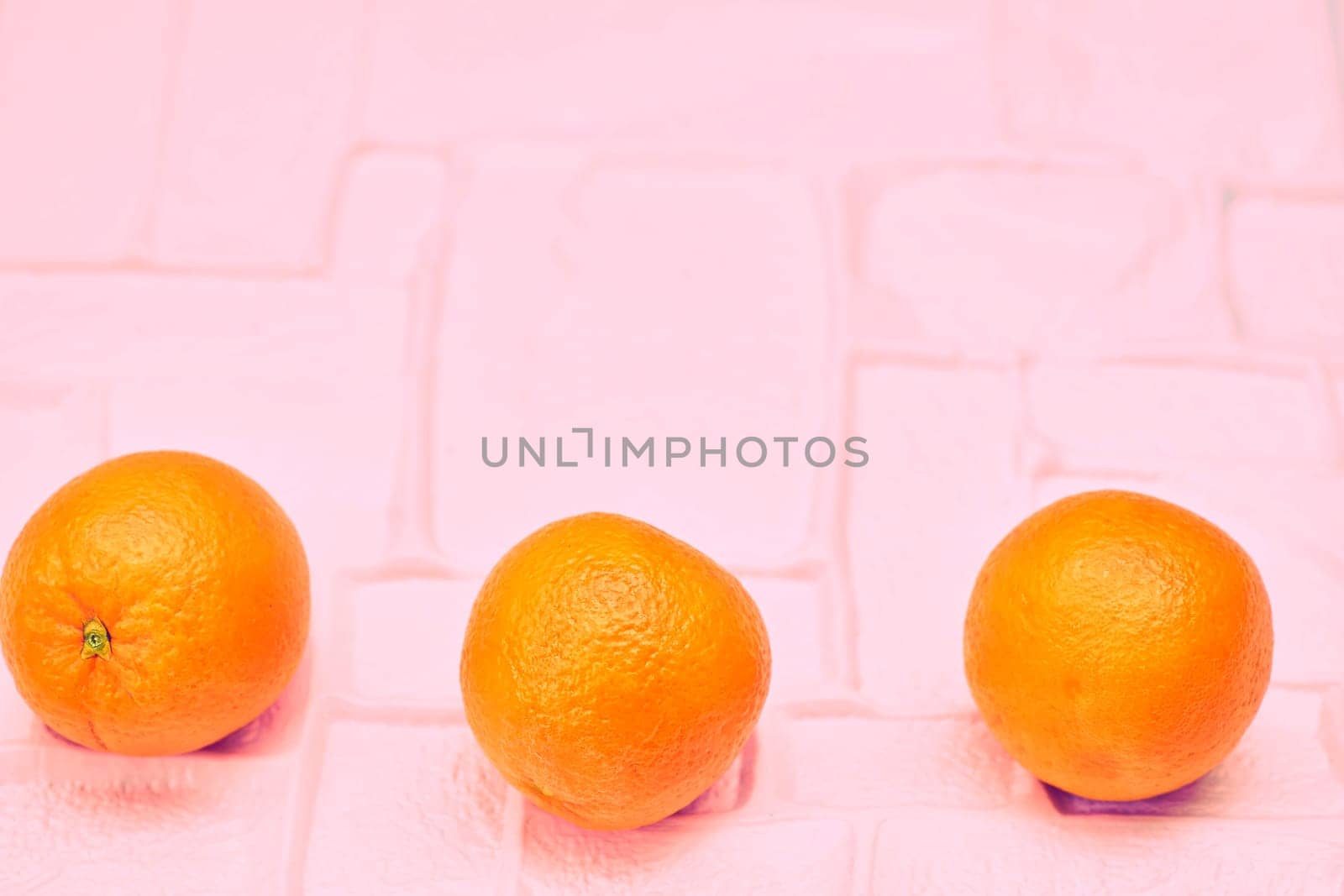 Three ripe oranges on pink, ready to eat and cook by jovani68