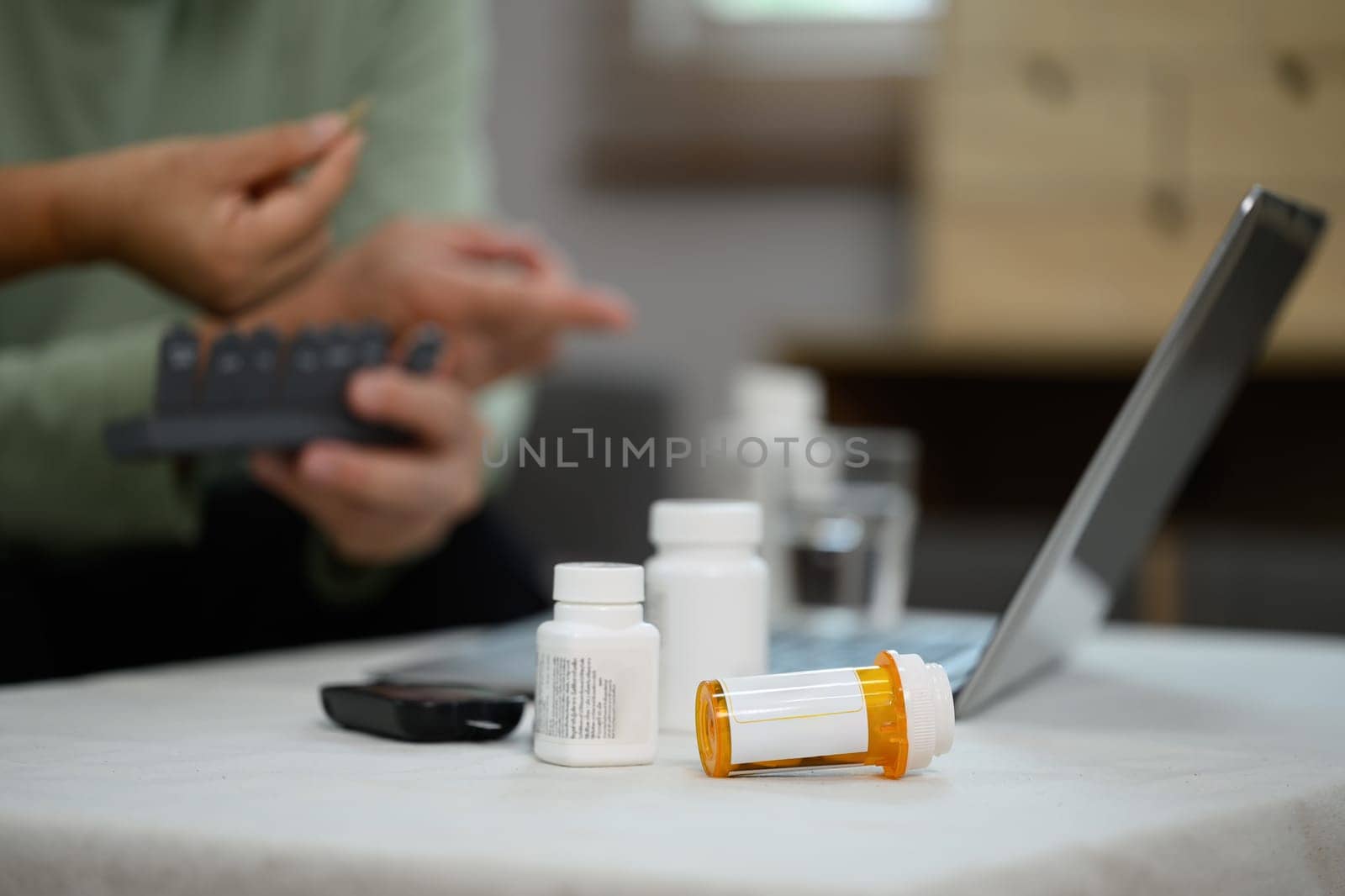 Focus on prescription pill bottles on table in living room and senior couple sitting on background.