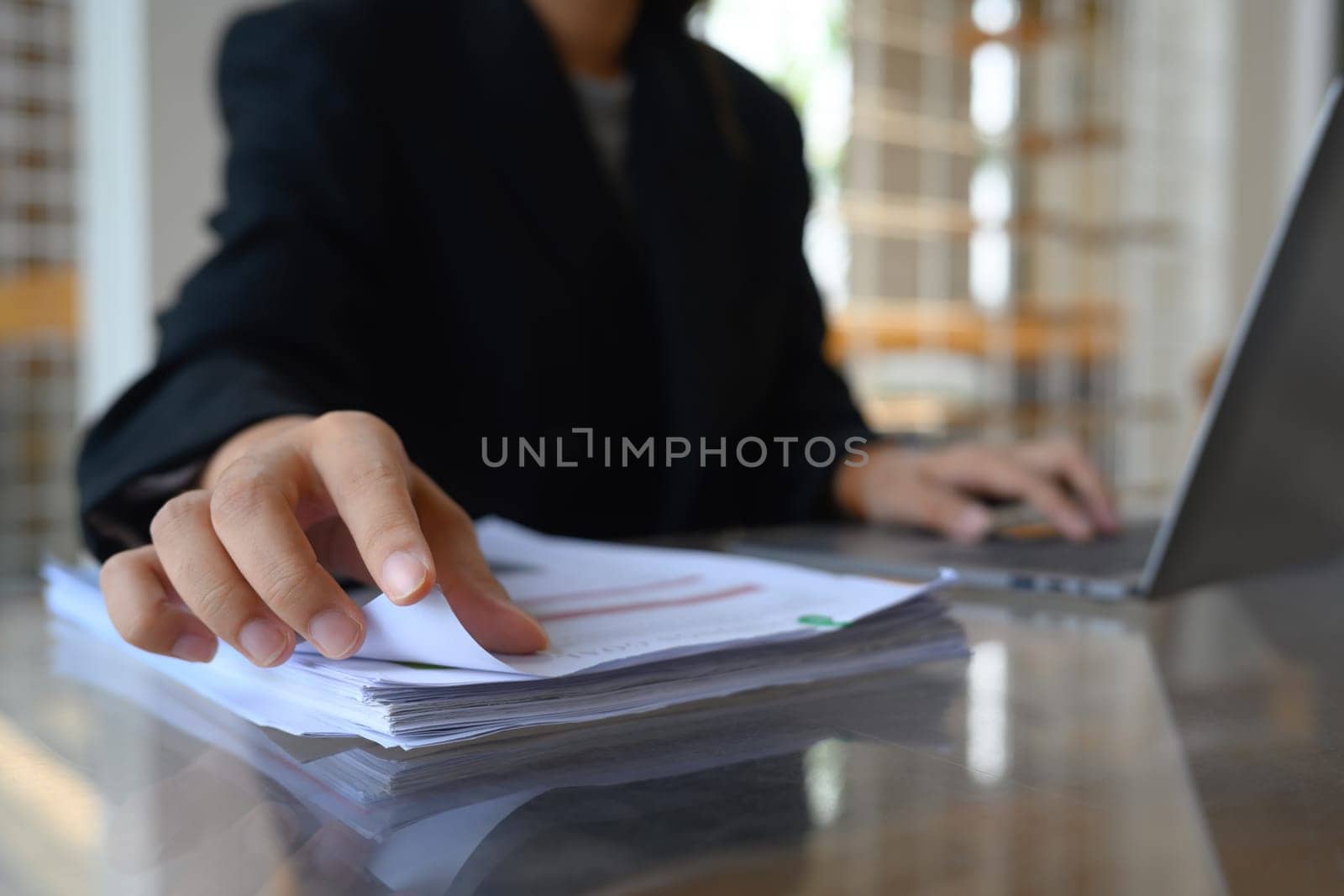Cropped shot male entrepreneur reading document at office desk by prathanchorruangsak