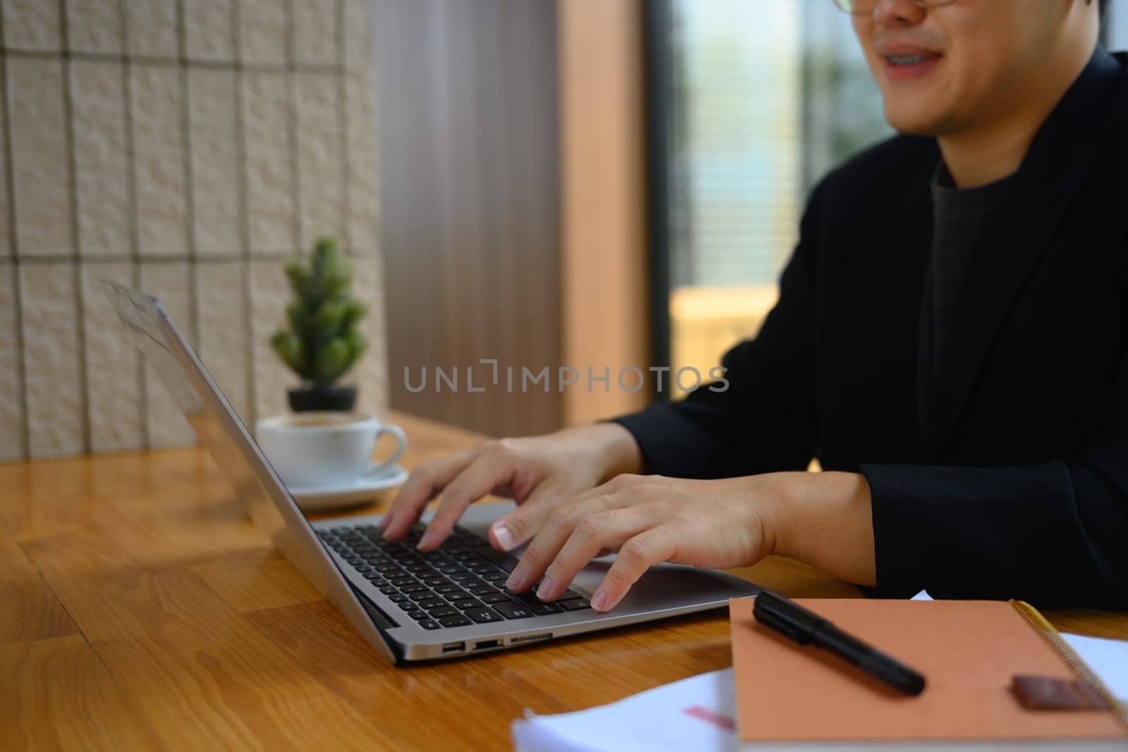 Smiling male worker hands typing on laptop keyboard answering email or searching information.
