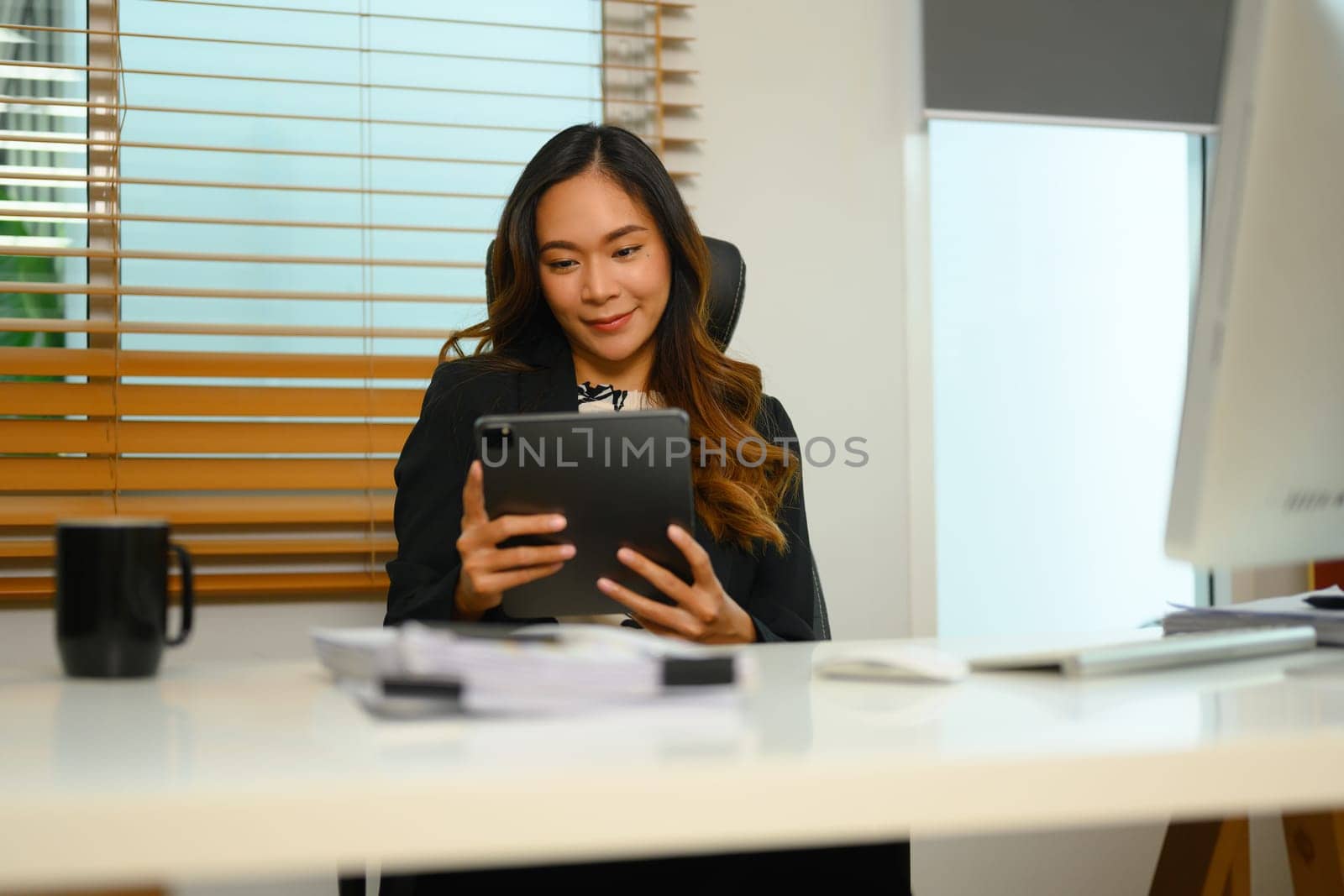 Beautiful businesswoman checking email on digital tablet in the morning by prathanchorruangsak