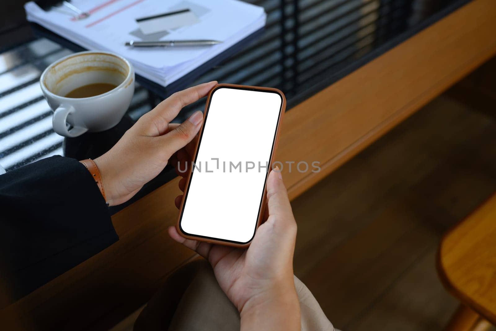 Close up businesswoman using mobile phone at desk. White empty screen for advertising text by prathanchorruangsak