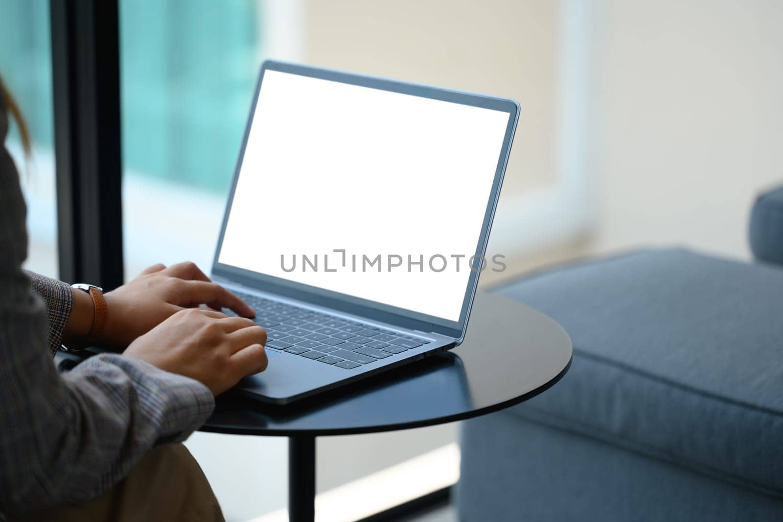 Cropped shot of young businesswoman using laptop at the lounge area of an office by prathanchorruangsak