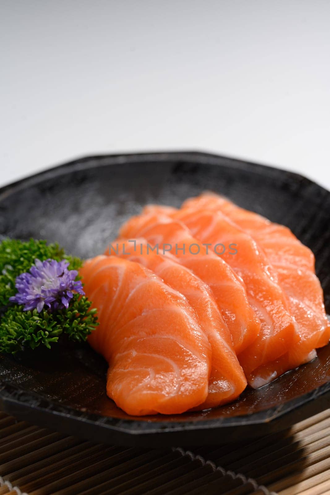 Sliced salmon with parsley leaf in black plate. Japanese food style.