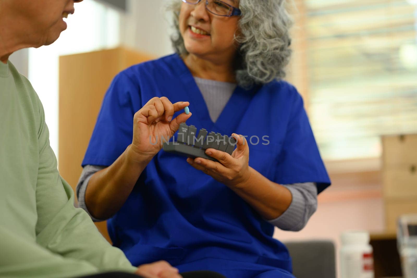 Smiling female doctor explaining medicine dosage to senior patient during home visit.