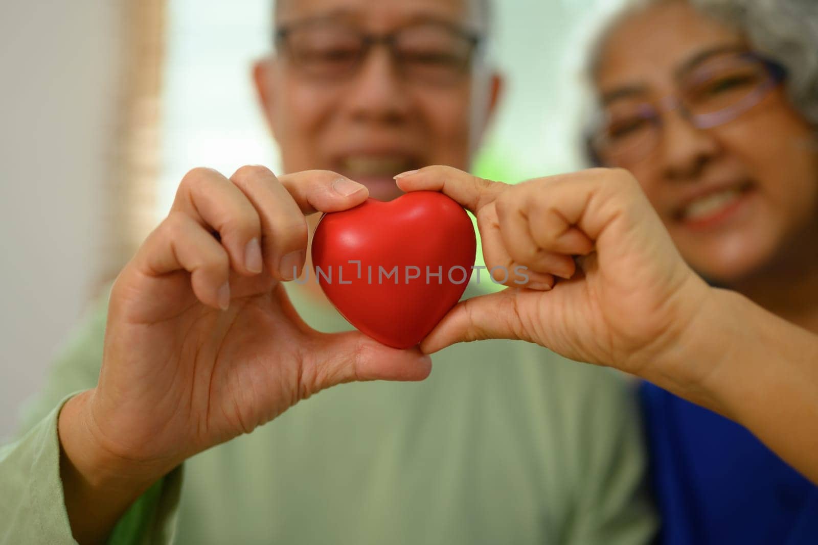 Happy seniors couple holding red heart. Love, health care and medical concept by prathanchorruangsak