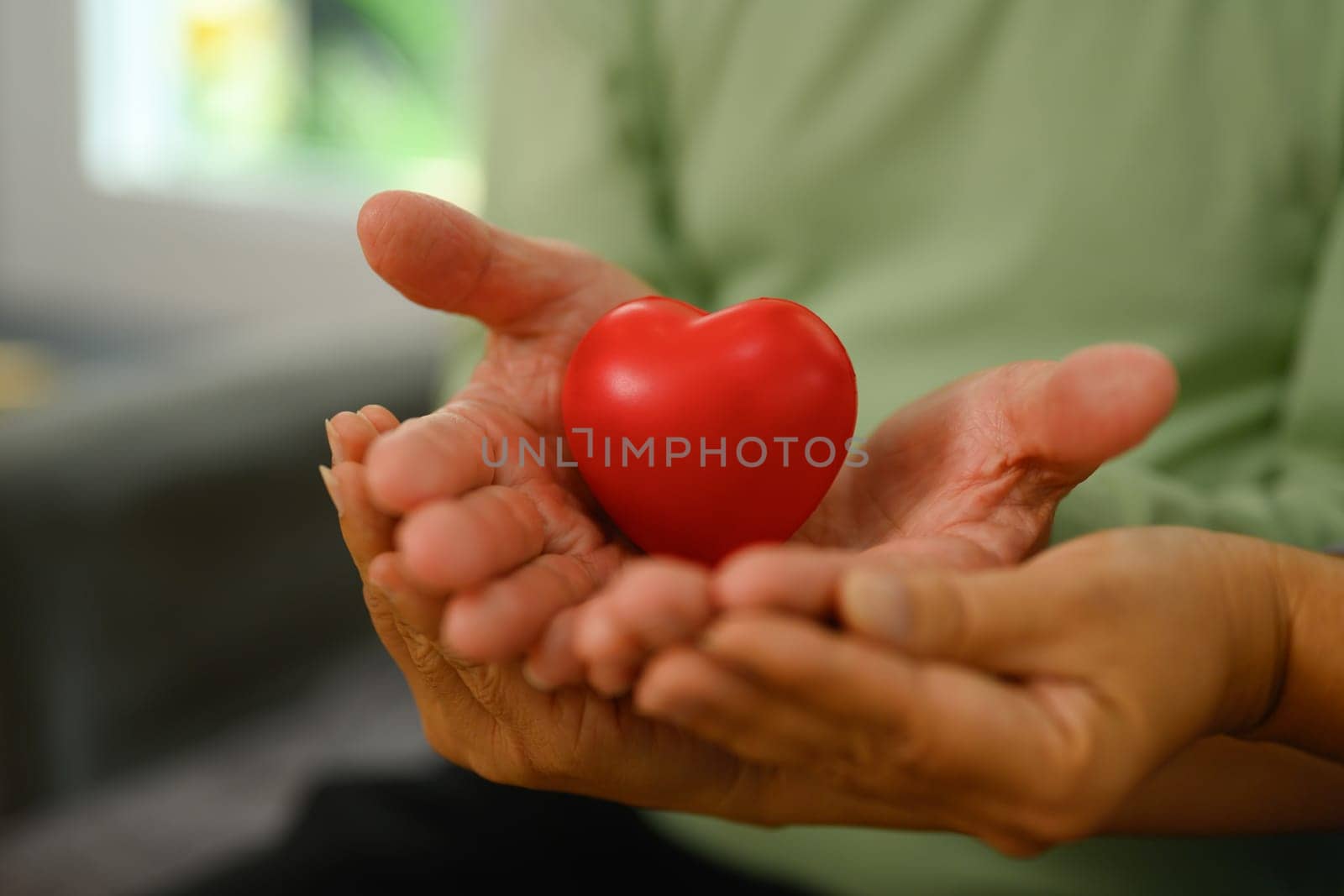 An elderly couple holding red heart symbol of love, health care, medical and charity concept by prathanchorruangsak