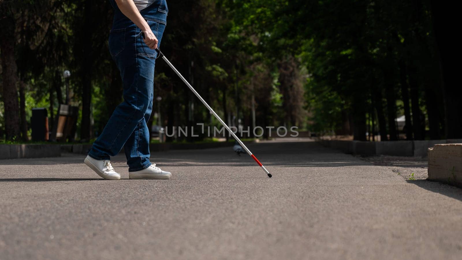 Blind woman crosses the street with the help of a tactile cane