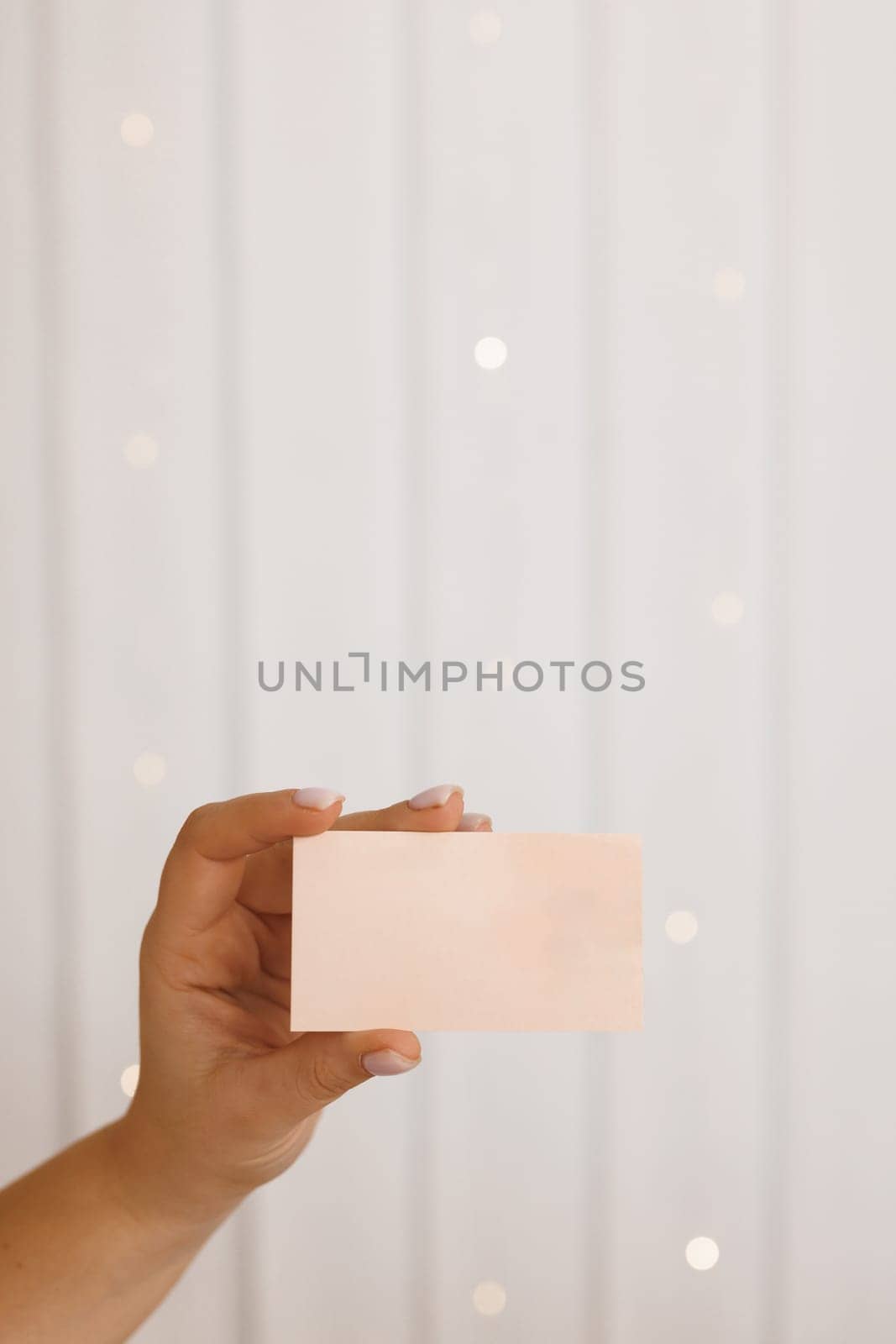 Woman hand holding empty business card, credit card or blank paper isolated on white background. Female hands, empty menu, discount card, business card on beauty background with copy space by uflypro