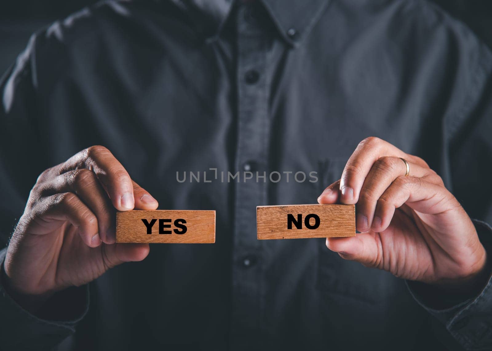 Hands of businessman holding wooden blocks with yes and no words portraying decision-making. Choice symbolizes business success. Think With Yes Or No Choice. by Sorapop