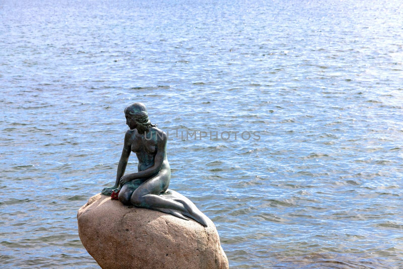 Symbol of Denmark the little mermaid sitting on a stone in Copenhagen, Denmark - April 22, 2024