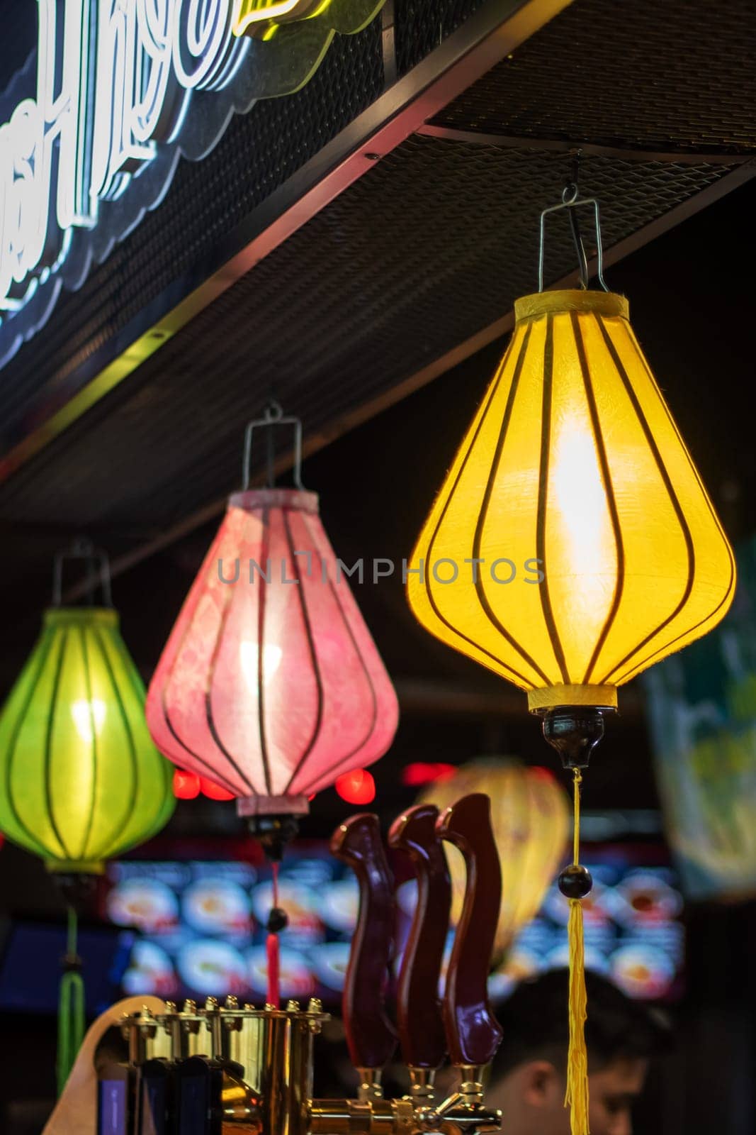 The restaurant is adorned with a row of colorful lanterns hanging from the ceiling, creating a vibrant atmosphere in the room