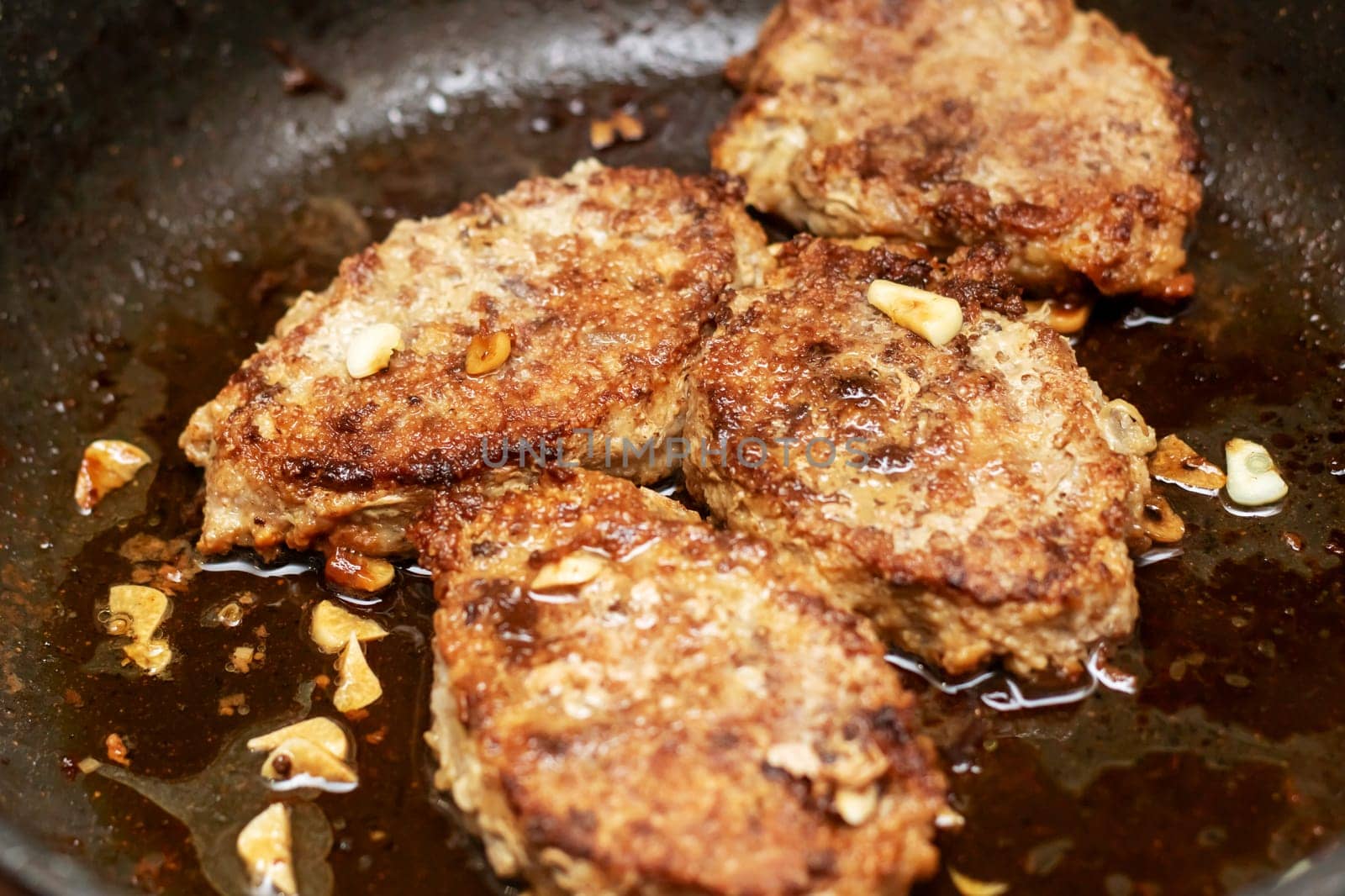 A cut of meat is sizzling in a frying pan, being cooked to perfection. This dish is a classic example of deep frying in cuisine, creating a delicious fried food ingredient