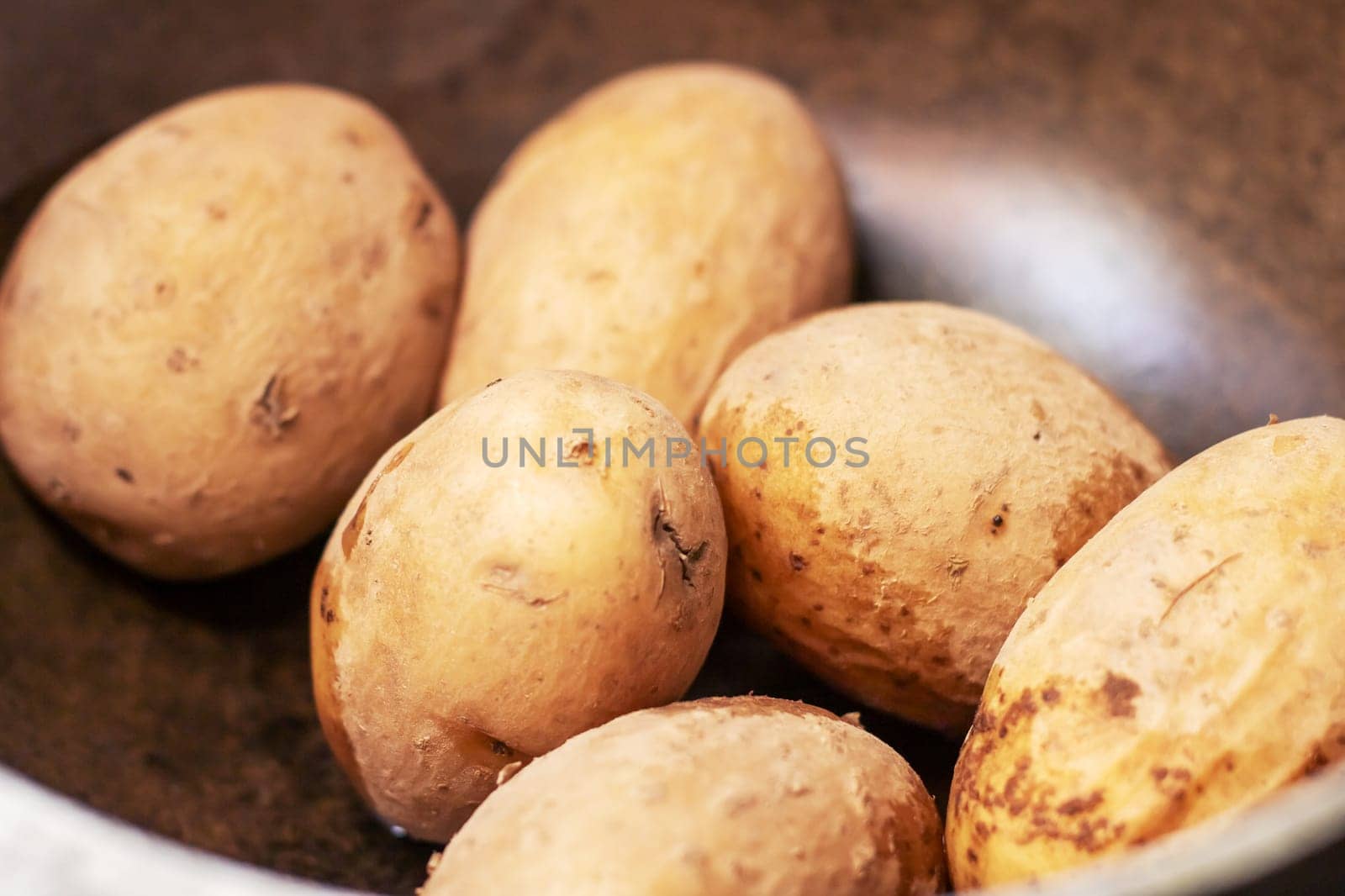 Potatoes, a staple food, are being cooked in a pan with water. These root vegetables are a natural food ingredient used in various cuisines