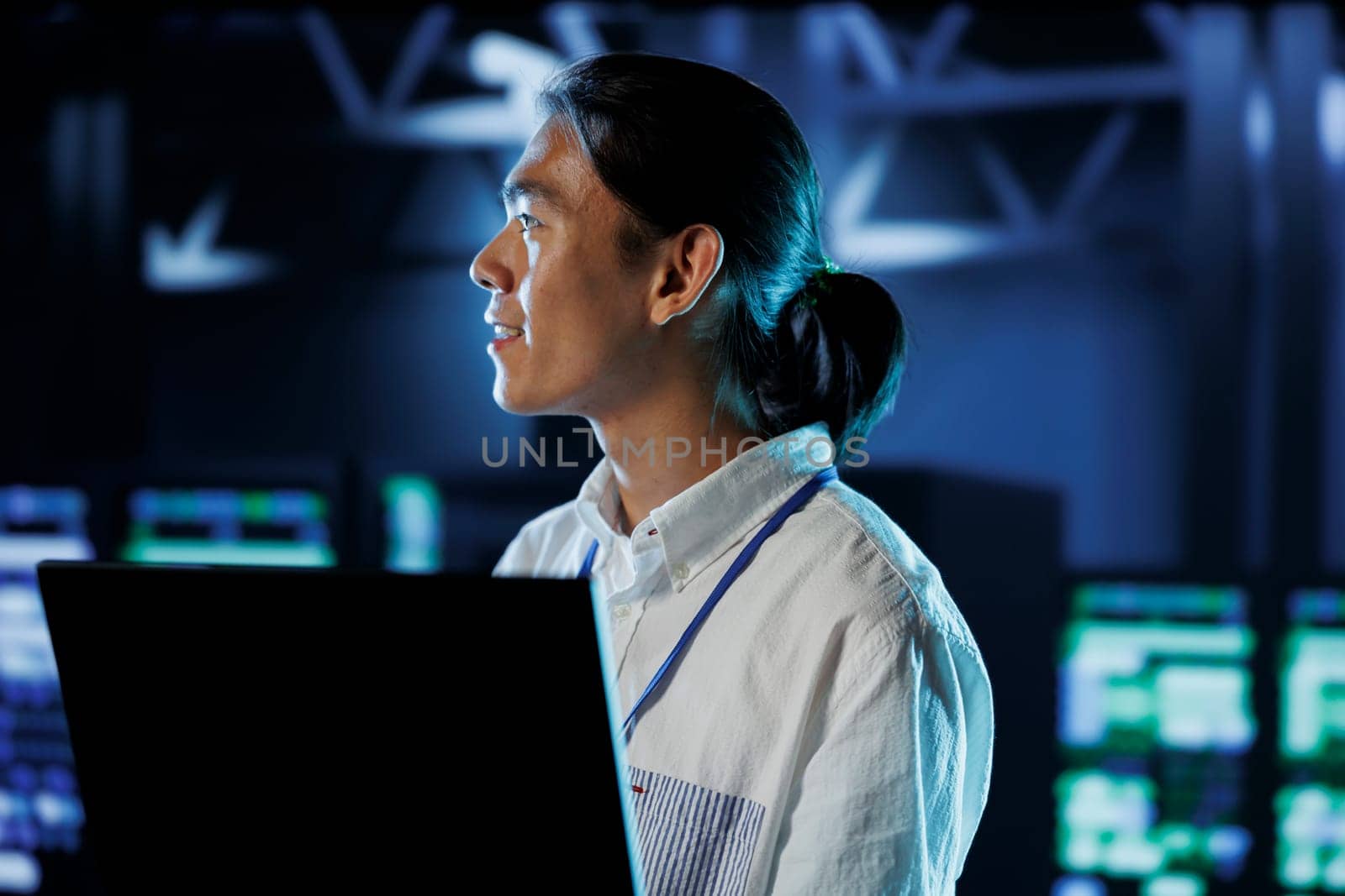 Cheerful BIPOC man between server hub rows providing processing resources for businesses worldwide. Computer scientist fixing data center mainframes tasked with managing massive databases