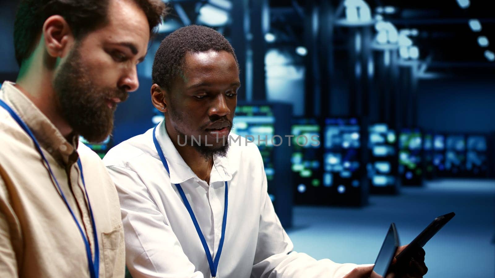 IT team running data center components diagnostic tests to determine and patch software issues. Workers using laptop and tablet to mend critical systems, checking for defects, close up