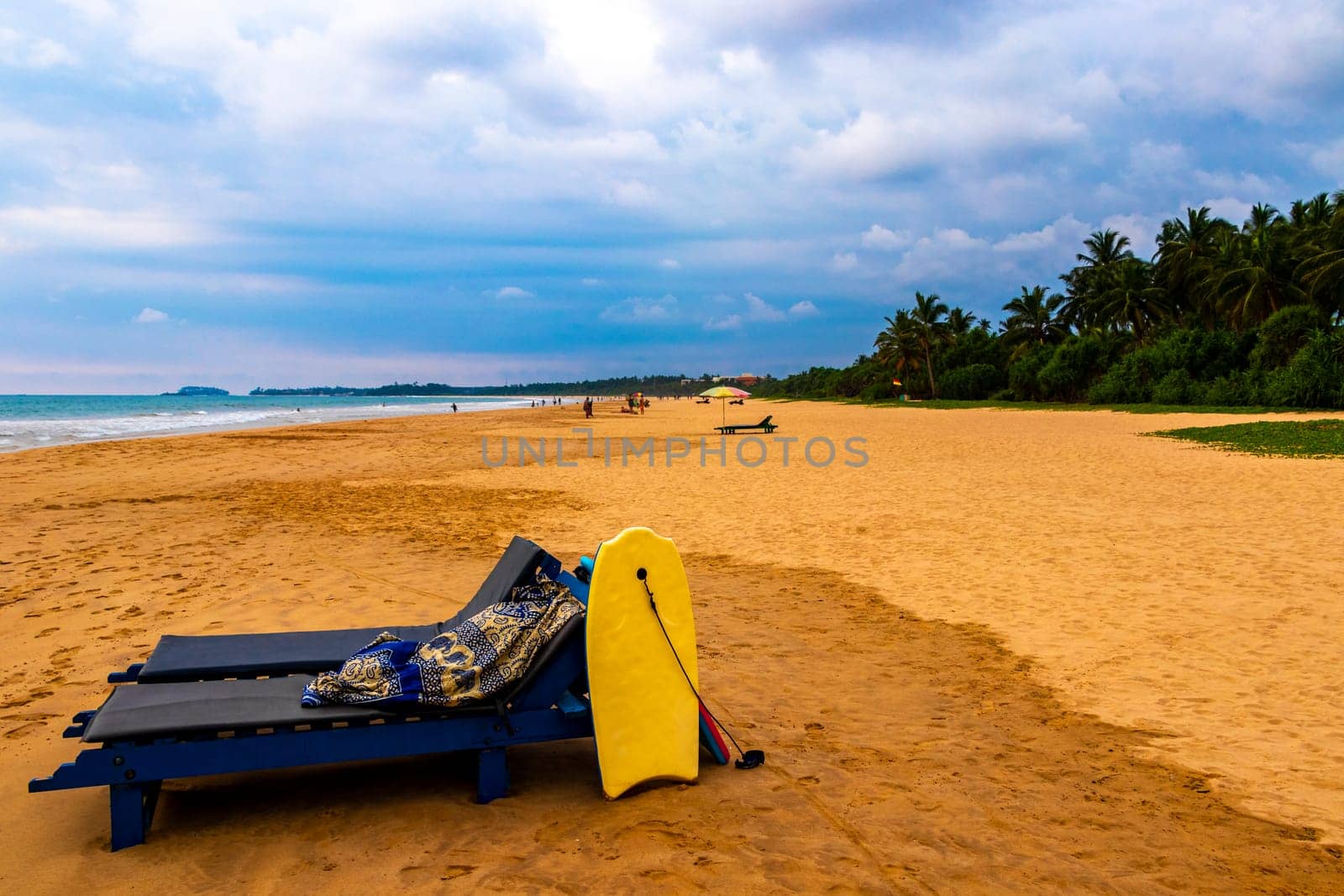 Beautiful beach with tropical nature sand water waves people fun parasols and sun loungers in Bentota Beach on Sri Lanka island.