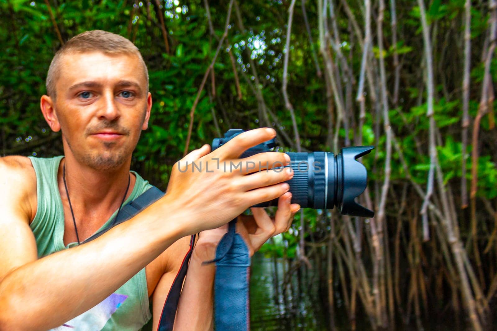 Young man male tourist with camera taking pictures on Boat safari trip through mangrove jungle forest in Bentota Ganga River Lake in Bentota Beach Sri Lanka.