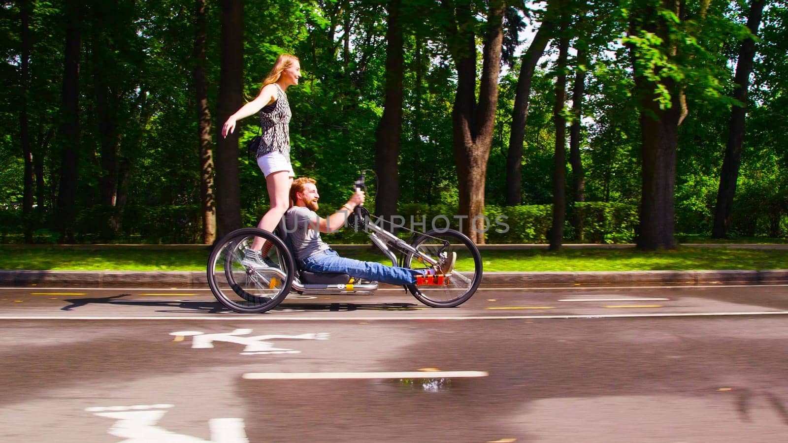 Happy young disable man is riding hand bike by Chudakov