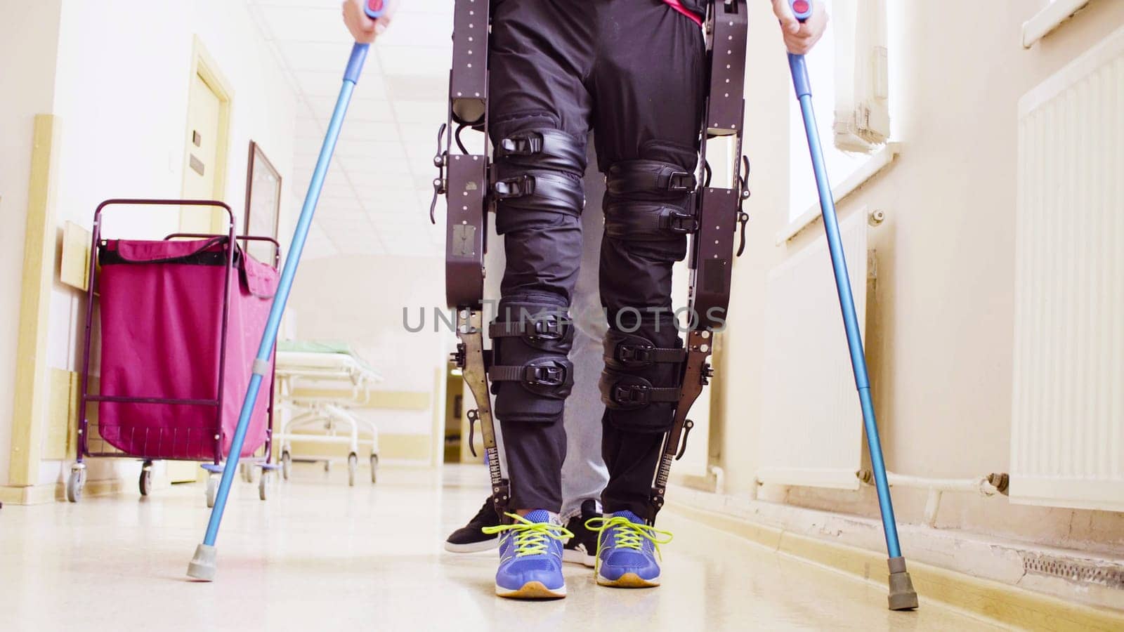 Legs of disable man in robotic exoskeleton by Chudakov