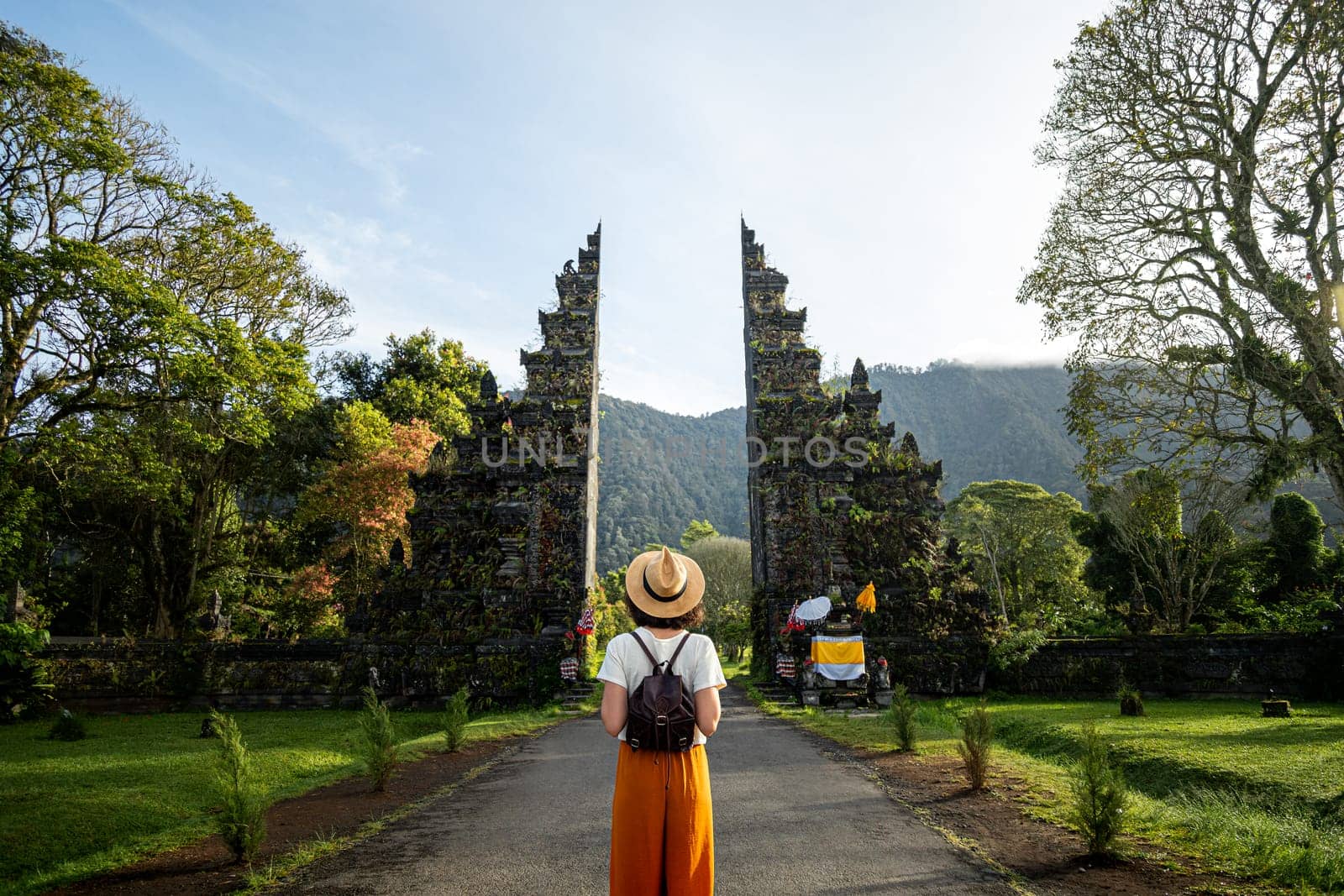 Woman tourist traveler with backpack enjoying walk through Balinese Hindu temple during vacation in Asia. Woman contemplating monument during holidays. Copy space. Traveling in Asia concept.
