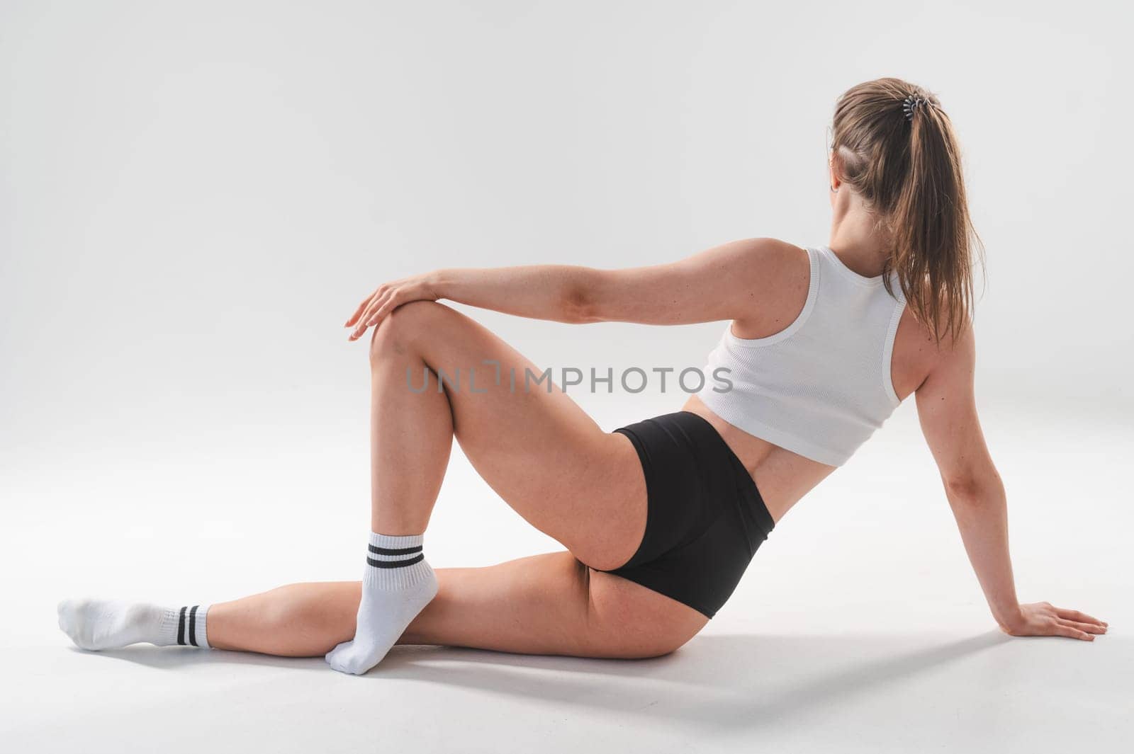 A woman in shorts sits with her back on a white floor. Beautiful butt