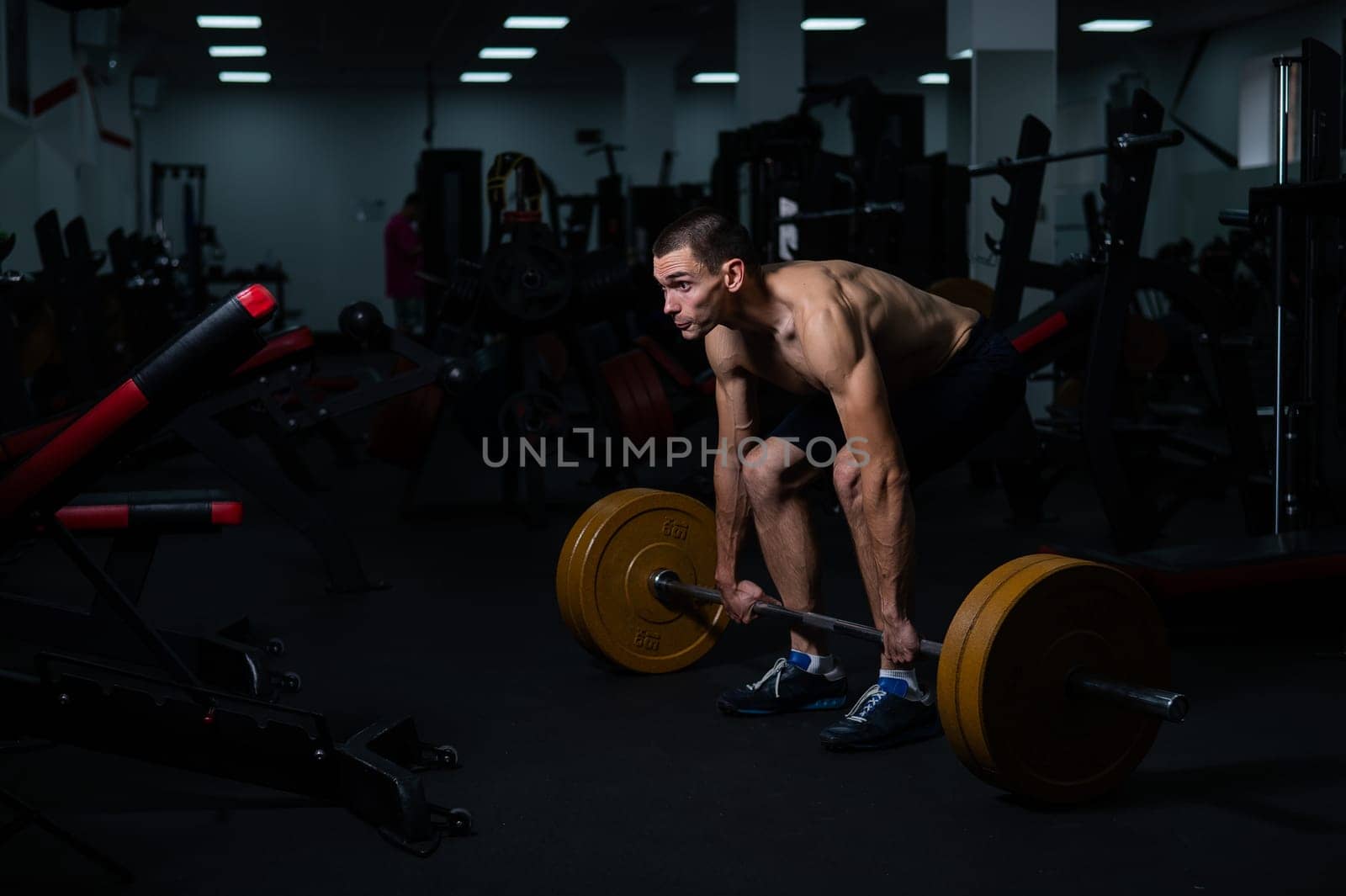 Shirtless man doing bicep exercises with dumbbells in the gym