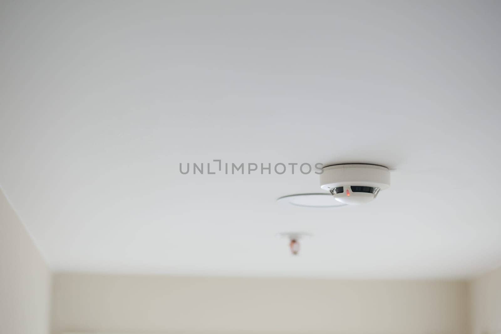 White smoke detector on ceiling at home by towfiq007