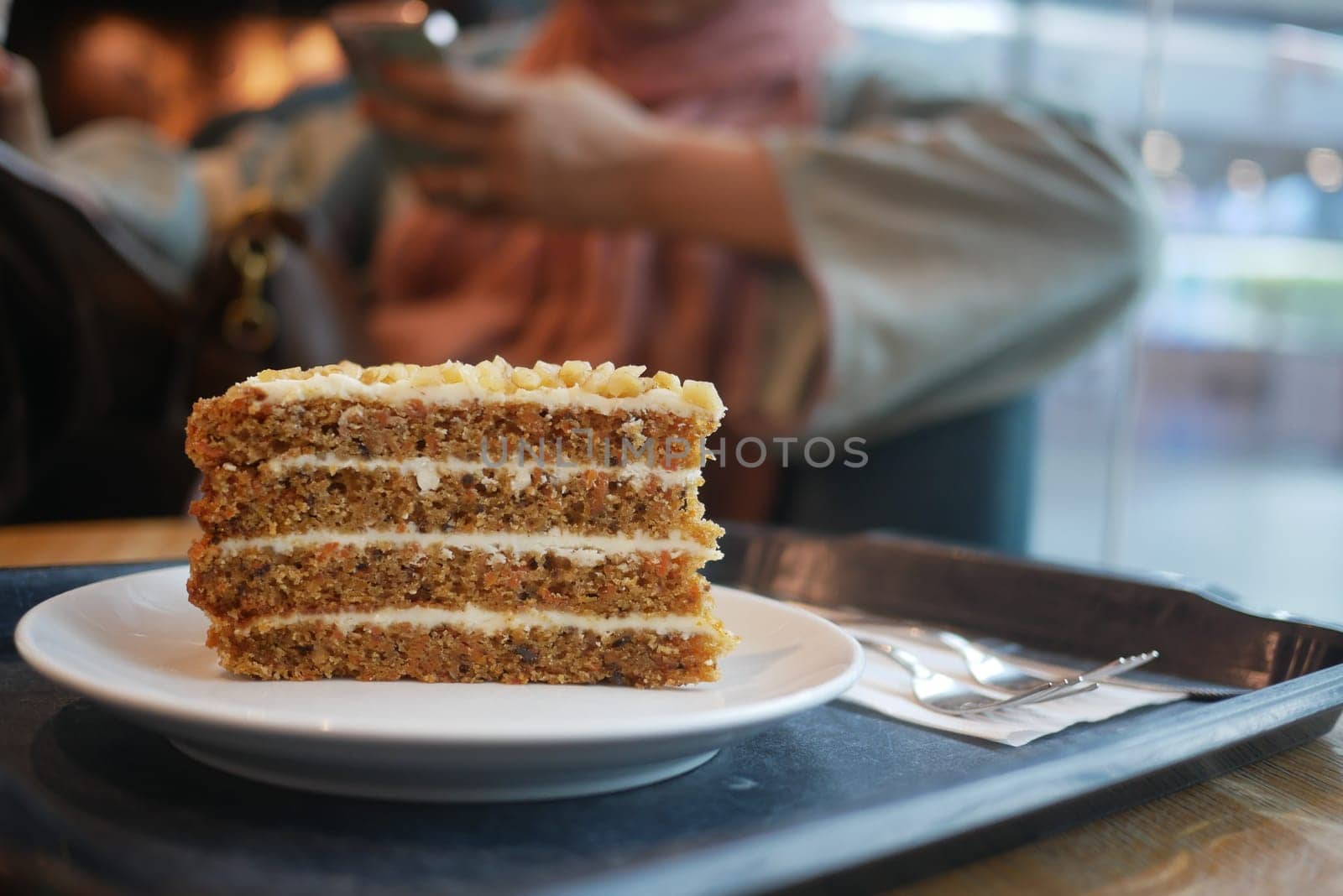 caramel cake on cafe table and a woman sitting on background ,