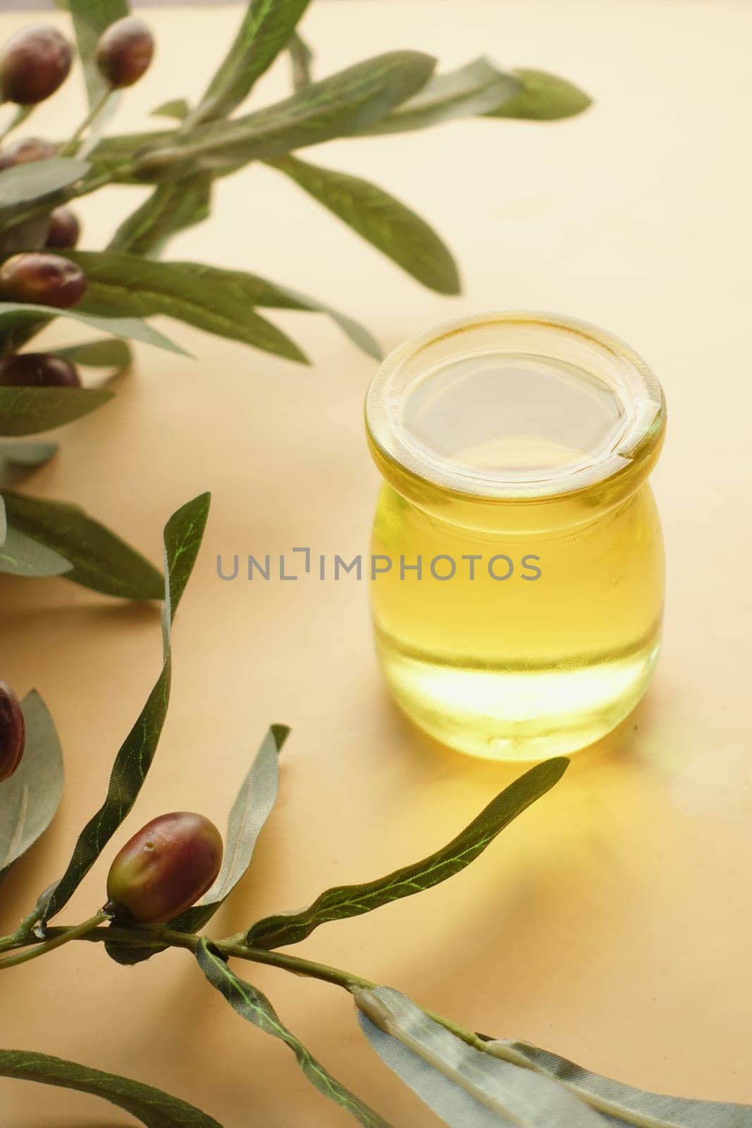 bottle of olive oil and olive leaves on yellow by towfiq007